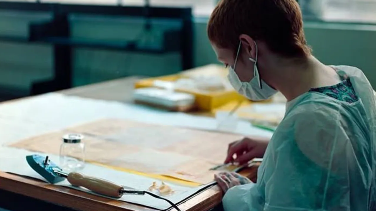 Marina Nabuco working at a table with archival material from the cordel collection